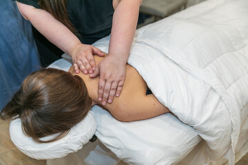 Obraz na płótnie Canvas Brunette woman message therapist giving a woman a shoulder massage at a local spa