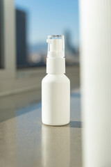 Plastic white bottles with pump for cream or lotion on the windowsill. Skin care cosmetic with...