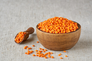 Red lentil  in wooden bowl on linen cloth. Close up