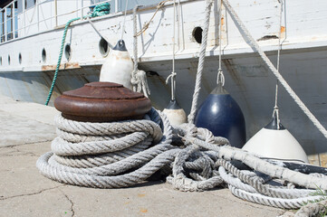 Obraz premium Nautical old ropes tied on the bollard and buoys securing an old abandoned rusted ship, in Zadar, Croatia