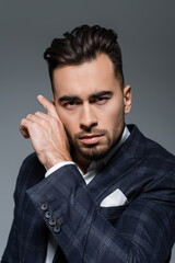 Naklejka premium young bearded businessman in checkered blazer looking at camera isolated on grey.