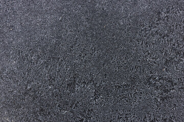 Frozen pattern of hoarfrost and frostwork structure on the dark windshield glass. Color photo for background. 