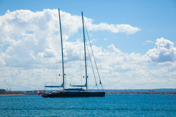 A large, sailing, two-masted yacht leaves the bay.