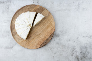 Top view, sliced round white cheese - a traditional dairy creamy dairy product on a wooden board plate. HOME, Country style..