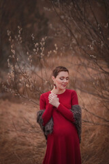 Beautiful pregnant girl. Girl pregnant with twins. Beautiful pregnant girl in nature. Early spring. Beautiful pregnant girl in a red dress. Pregnant girl with short hair