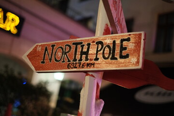 Snow covered sign pointing to the North Pole santa