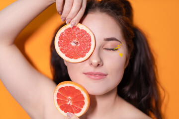 young woman girl with grapefruit slice on orange background.