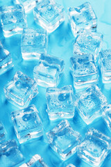 Lots of ice cubes with water drops scattered on a blue background