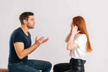 Studio shot of resentful dissatisfied young couple quarreling, actively gesturing with hands, talking and shouting at each other on white isolated background. Concept of relationship crisis.