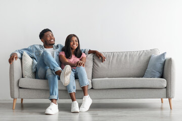 Fototapeta na wymiar African American couple spending weekend together sitting on couch