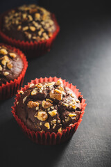 Homemade chocolate muffins or cupcakes sprinkled of nuts on dark background