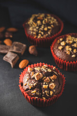 Homemade chocolate muffins or cupcakes sprinkled of nuts on dark background