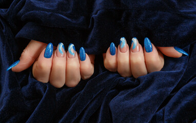 Female hands with a multicolored manicure on dark blue background closeup