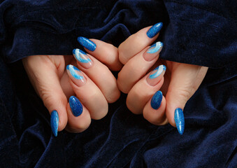Female hands with a multicolored manicure on dark blue background closeup