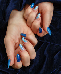 Female hands with a multicolored manicure on dark blue background closeup