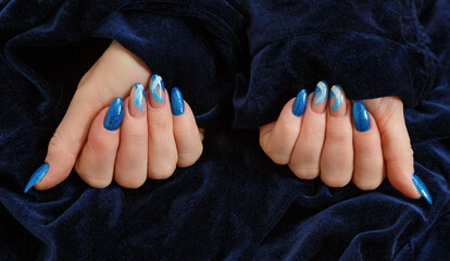 Female hands with a multicolored manicure on dark blue background closeup