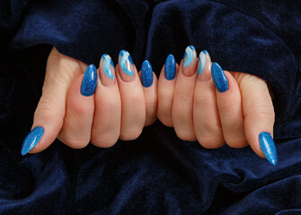 Female hands with a multicolored manicure on dark blue background closeup