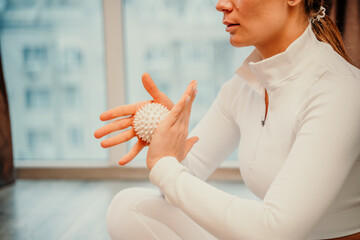 Athletic slim caucasian woman doing thigh self-massage with a massage ball indoors. Self-isolating...