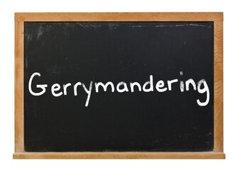 Gerrymandering written in white chalk on a black chalkboard isolated on white