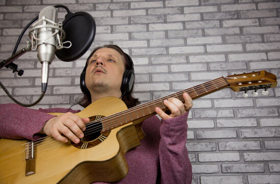 Man plays guitar. Young man plays a musical instrument. Musician records his composition in a music Studio
