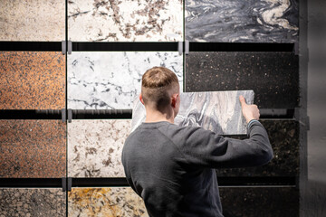 a man in the granite tile department applies one sample to another to select a material for home...