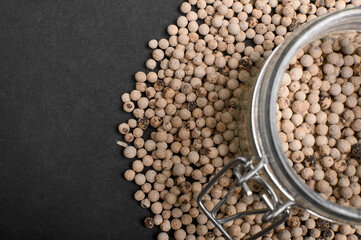 dried white pepper in a jar close-up on a black background