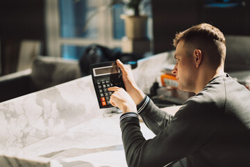a man sits on a chair and counts an offer for a client on a calculator, cost calculation