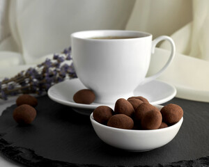 Chocolate candies and a cup of tea on a gray board.