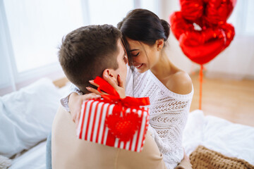 Valentine's Day concept. Lovers give each other gifts. Young couple at home celebrating Valentine's Day.