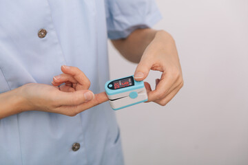 Pulse oximeter with hand of doctor isolated on white. Measuring oxygen saturation, pulse rate and oxygen levels. The concept of portable digital device to measure person's oxygen saturation.