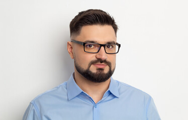 Portrait of a business man with a beard in glasses and a shirt on a white background.