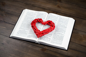 Open book, Bible. On the table. Red heart. The concept of love for God and Scripture.