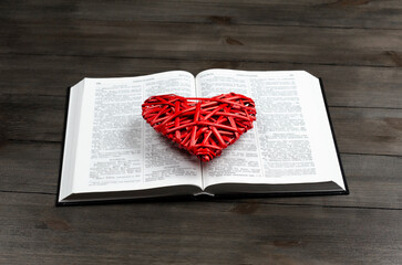 Open book, Bible. On the table. Red heart. The concept of love for God and Scripture. - obrazy, fototapety, plakaty