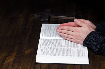 Prayer. Open Bible. Hands folded in prayer. The man is praying. Hands on the table.