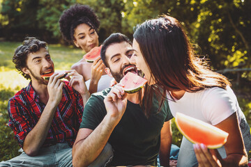 group of friends enjoying watermelon slices in the countryside having fun together on a weekend activity