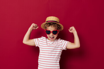Cheerful boy wearing sunglasses posing fashion red background