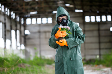 A dosimetrist scientist radiation inspector in protective clothing and a gas mask examines the...