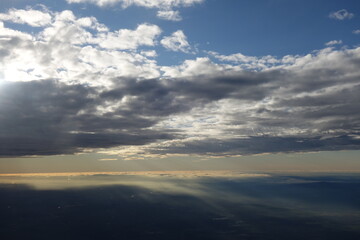Bright blue sky with white clouds hiding the sun