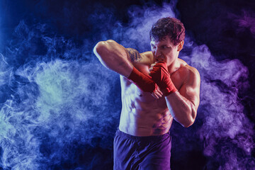 Kickboxer delivering elbow hit isolated on smoke background. Concept of sport, mixed martial arts. 