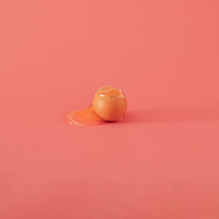 broken egg on the table against pink coral background. minimal creative decoration idea