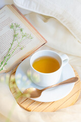 Tea cup next to book and leaves. Relax moment.