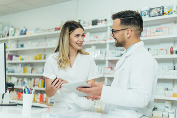 Happy young male and female colleagues pharmacist working in a pharmacy