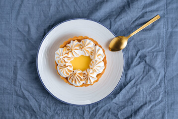 Lemon tart decorated with wiped cream. Decorated with flowers and different cloths and golden spoon. Lemon custard cream and sweet dough.