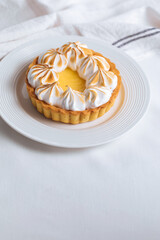 Lemon tart decorated with wiped cream. Decorated with flowers and different cloths and golden spoon. Lemon custard cream and sweet dough.