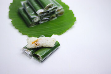 Indonesian traditional snack called Lemper on banana plate isolated on white background. Lemper is made from sticky rice and usually contains shredded or minced chicken and is wrapped in banana leaves