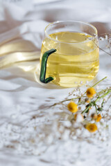 Cup of chamomile tea in transparent mug served with slice of lemon and orange. Tea break. 