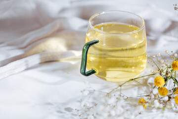Cup of chamomile tea in transparent mug served with slice of lemon and orange. Tea break. 