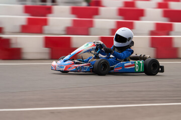 A child is racing on a small racing car on a sports court. Blur in motion. Selective focus.