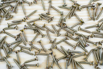 A pile of screw scattered on a wood bg. Close up, top view.