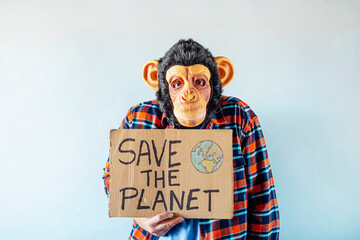 Man with monkey mask showing a sign that says SAVE THE PLANET.